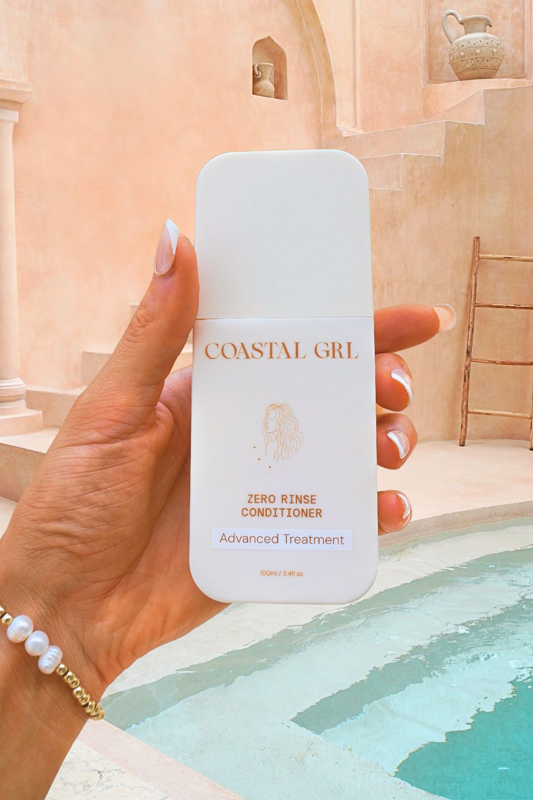 Coastal GRL Zero Rinse Conditioner bottle held beside a pool and terracotta wall