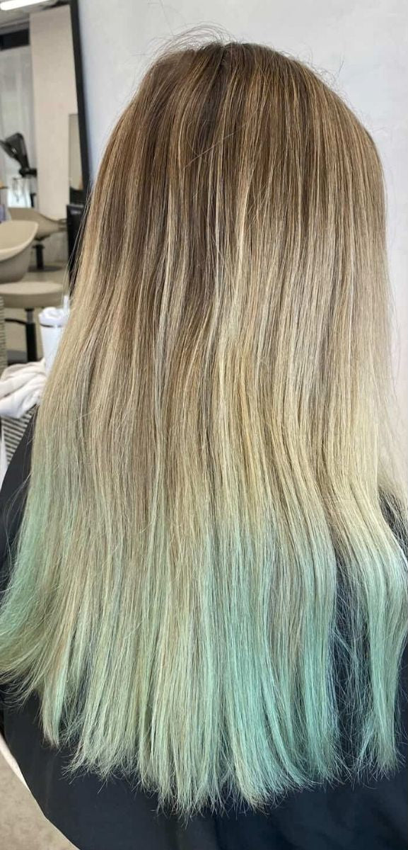 A side-by-side comparison of a person's long, straight hair from the back. The left side shows the hair in its natural state with a warm brown root and a mint green ombre transition at the ends.