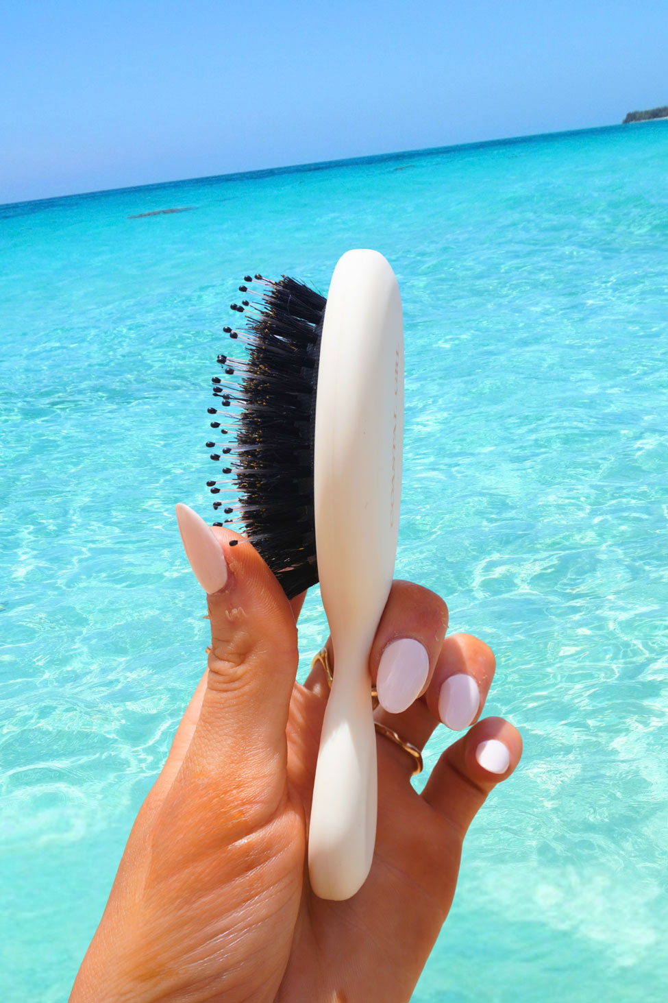 Side view of the Coastal GRL detangling brush bristles held against the ocean